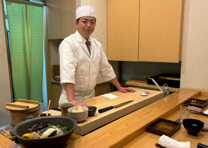 The smiling chef behind the counter at Sushi Tenkawa.